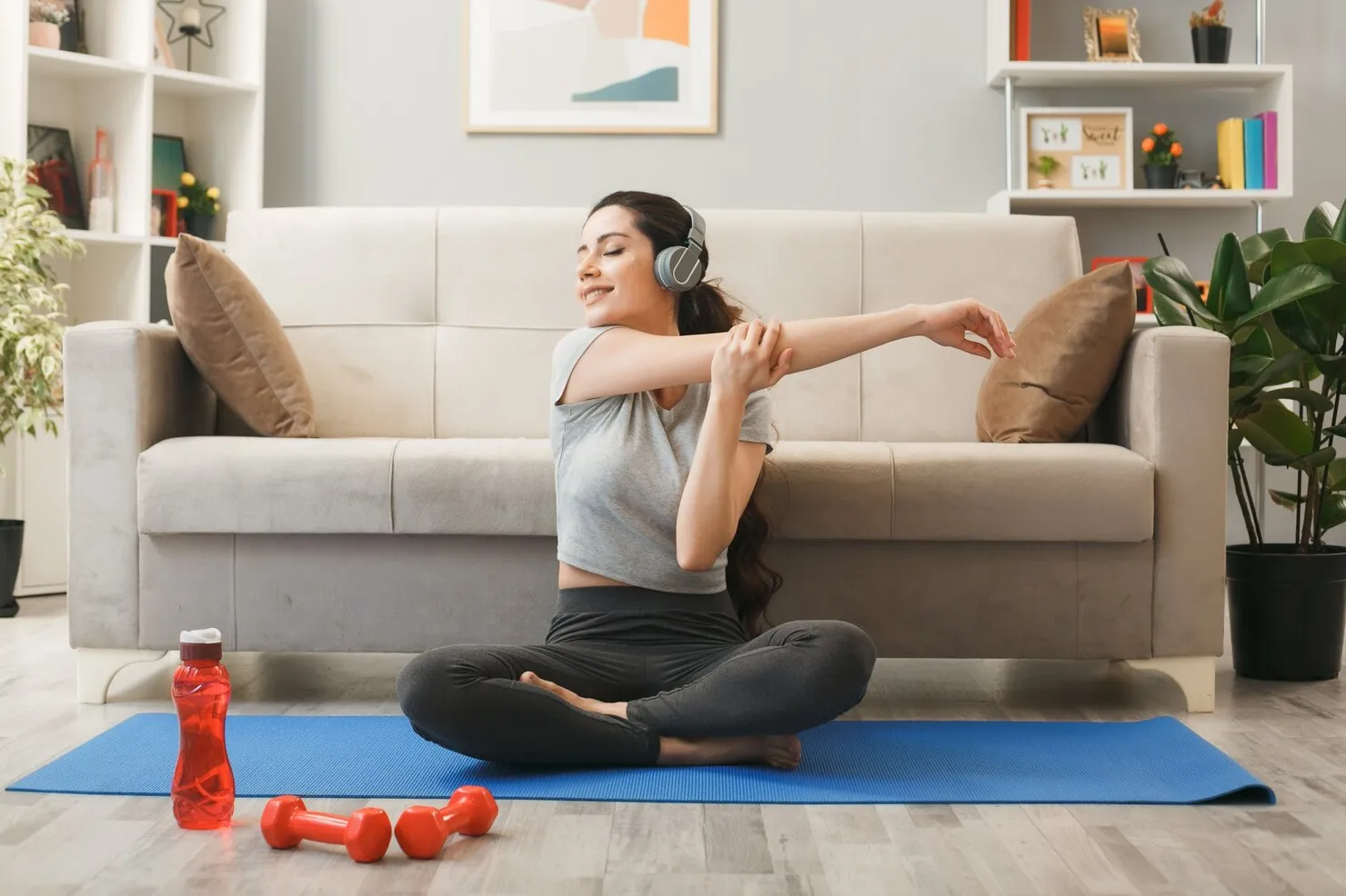 smiling-with-closed-eyes-young-girl-wearing-headphones-exercising-yoga-mat-front-sofa-living-room_141793-122866